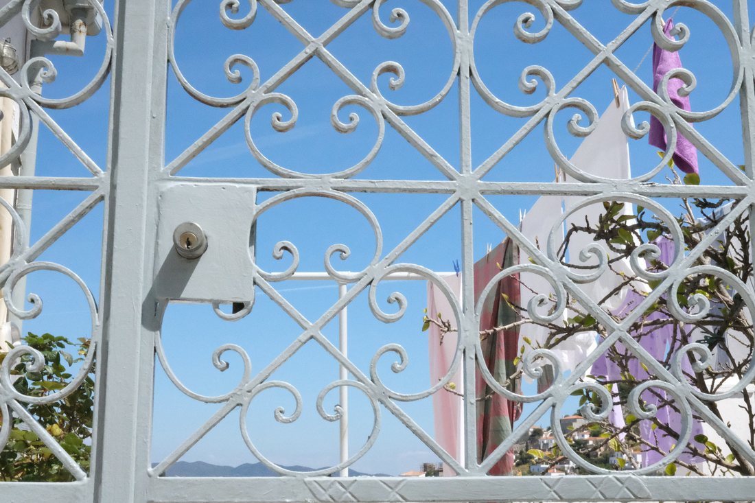 A white wrought iron gate with laundry hanging behind it