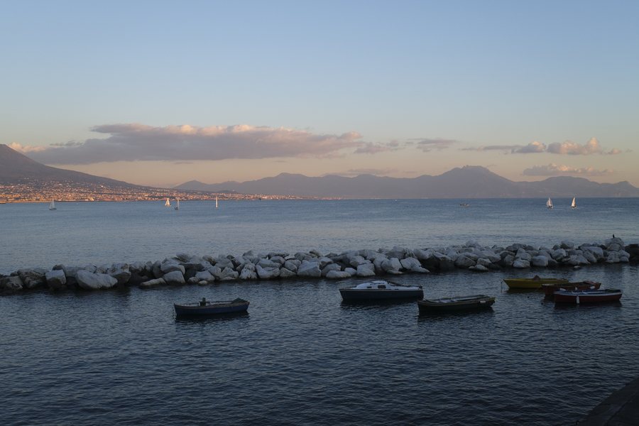 Small fishing boats moored behind a stone breakwater at sunset